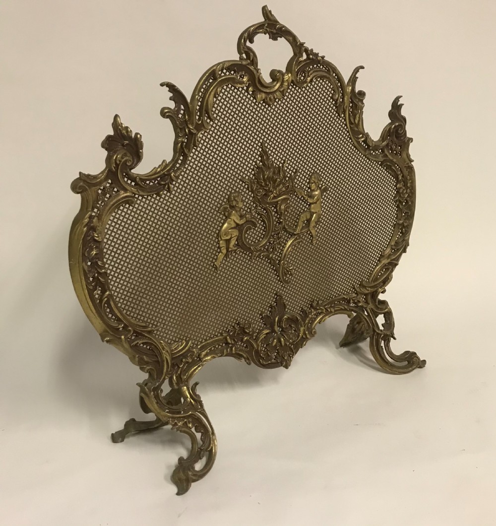 An ornate French Rococo style gilded bronze fire screen with a central cherub motif and fine metal mesh. View II