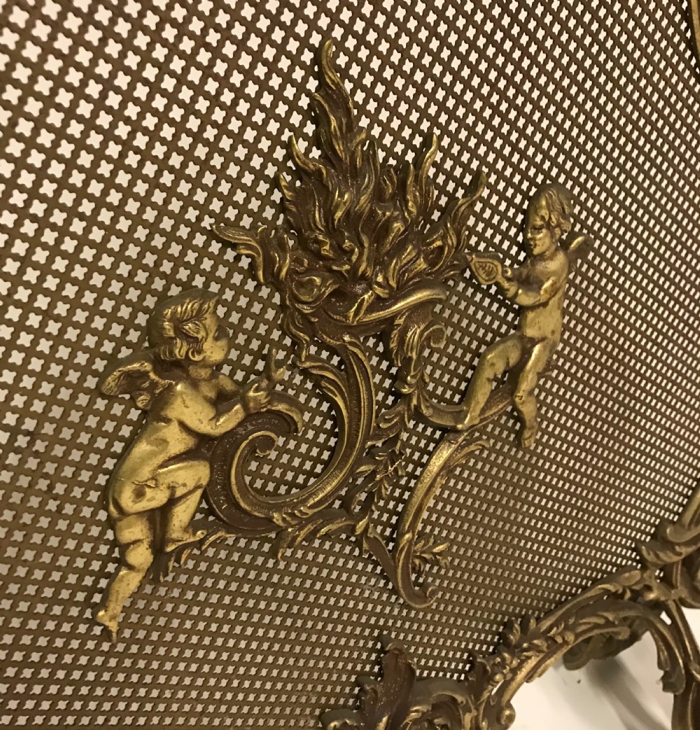 An ornate French Rococo style gilded bronze fire screen with a central cherub motif and fine metal mesh. View IV
