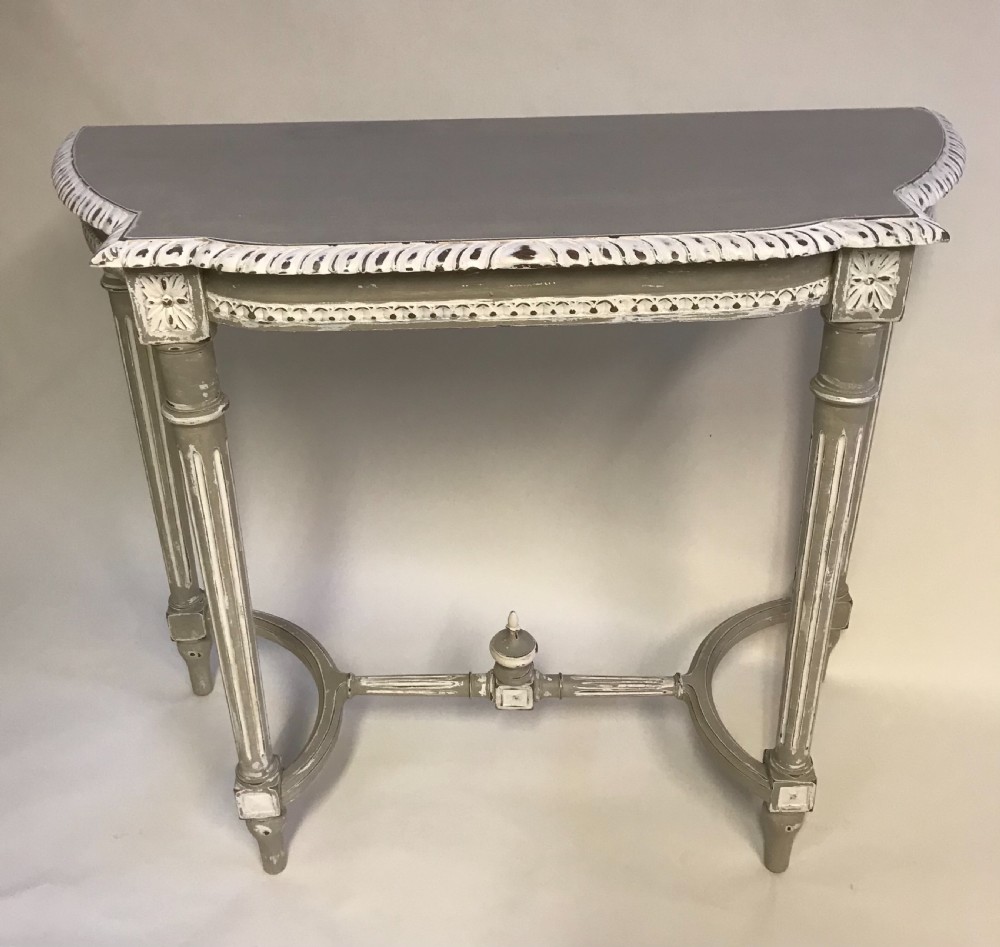 A French Louis XVI style painted console table in grey and white featuring fluted legs, carved rosettes, and an arched stretcher with a central finial. View V