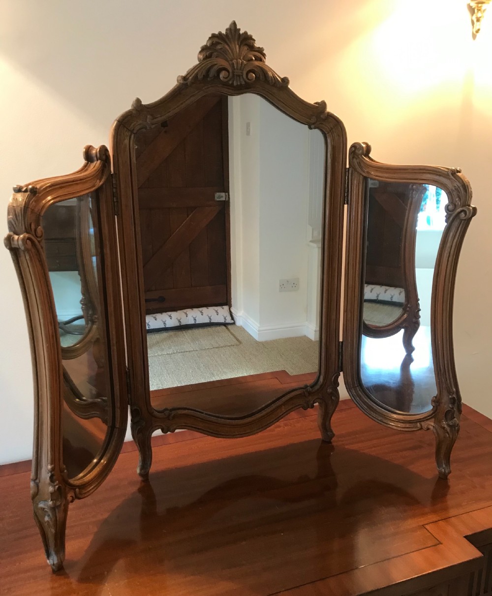 A three-panel French walnut dressing table mirror with carved acanthus leaf crest and cabriole feet.