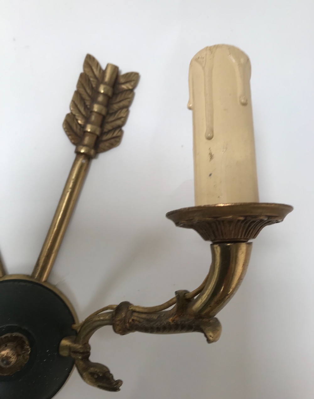 A pair of French brass twin-arm wall lights with a crossed arrow motif and dark circular backplates. View III