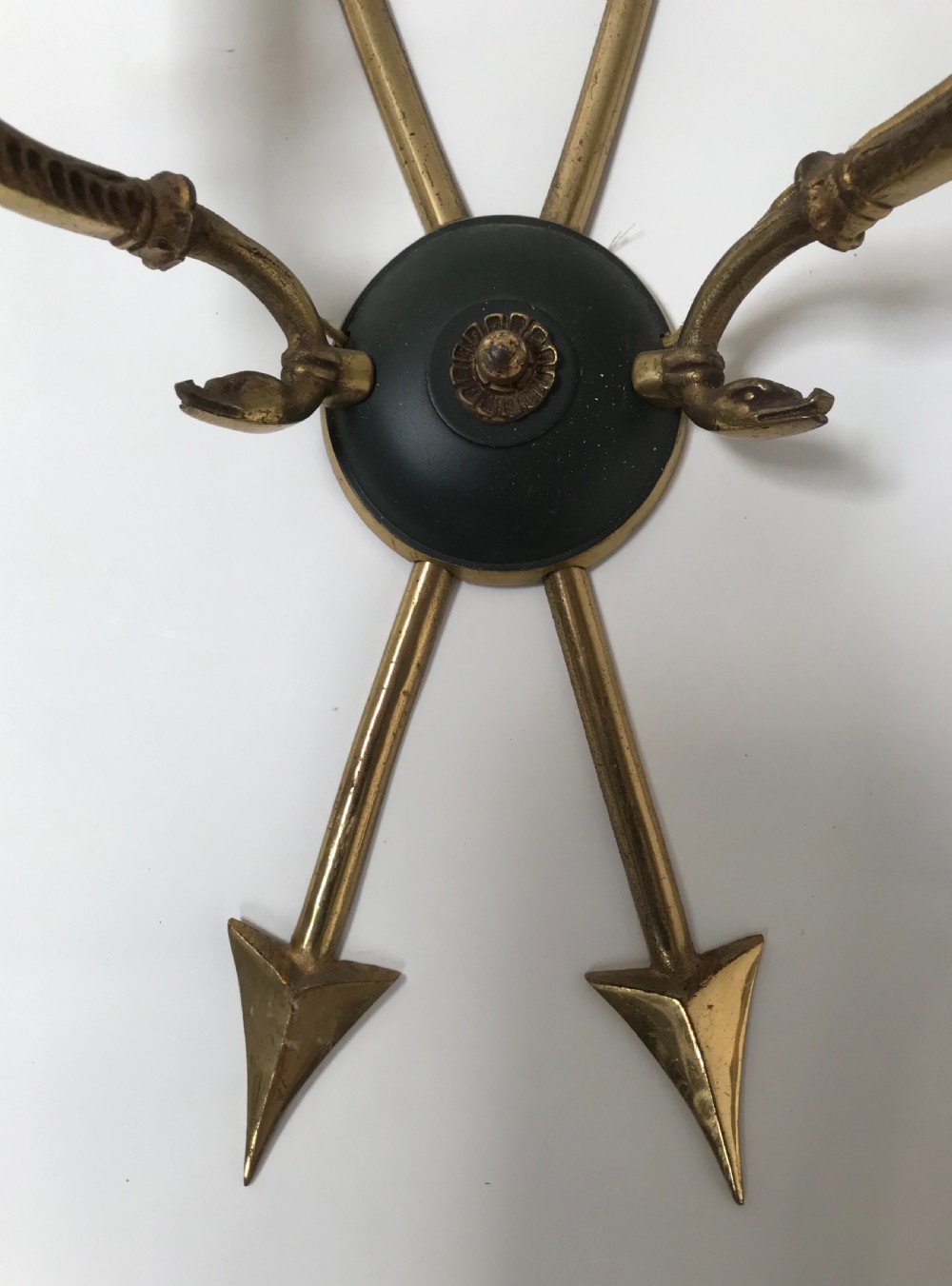 A pair of French brass twin-arm wall lights with a crossed arrow motif and dark circular backplates. View IV