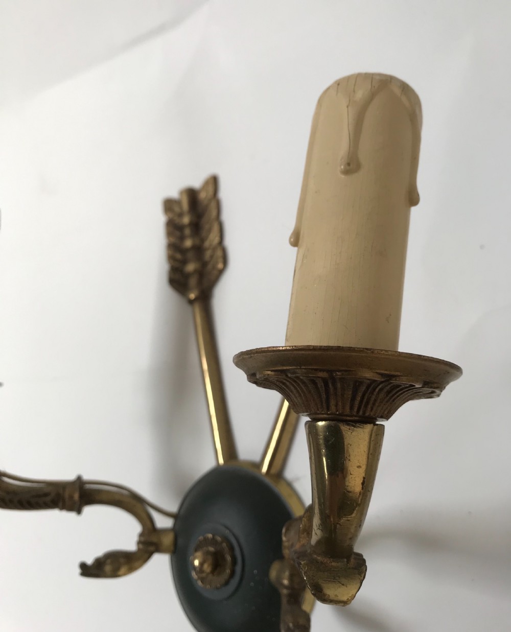 A pair of French brass twin-arm wall lights with a crossed arrow motif and dark circular backplates. View V