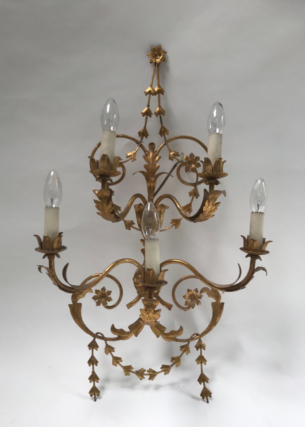 A French gilded metal five-light wall sconce decorated with scrollwork, leaf foliage, and flower-shaped candle cups.
