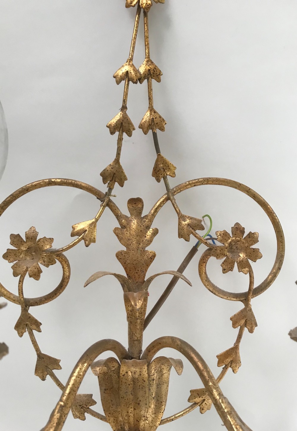 A French gilded metal five-light wall sconce decorated with scrollwork, leaf foliage, and flower-shaped candle cups. View II