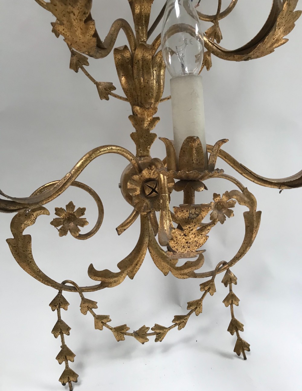 A French gilded metal five-light wall sconce decorated with scrollwork, leaf foliage, and flower-shaped candle cups. View III