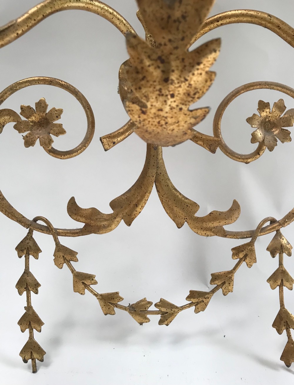 A French gilded metal five-light wall sconce decorated with scrollwork, leaf foliage, and flower-shaped candle cups. View V