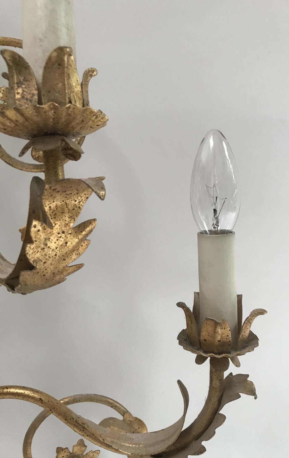 A French gilded metal five-light wall sconce decorated with scrollwork, leaf foliage, and flower-shaped candle cups. View VI