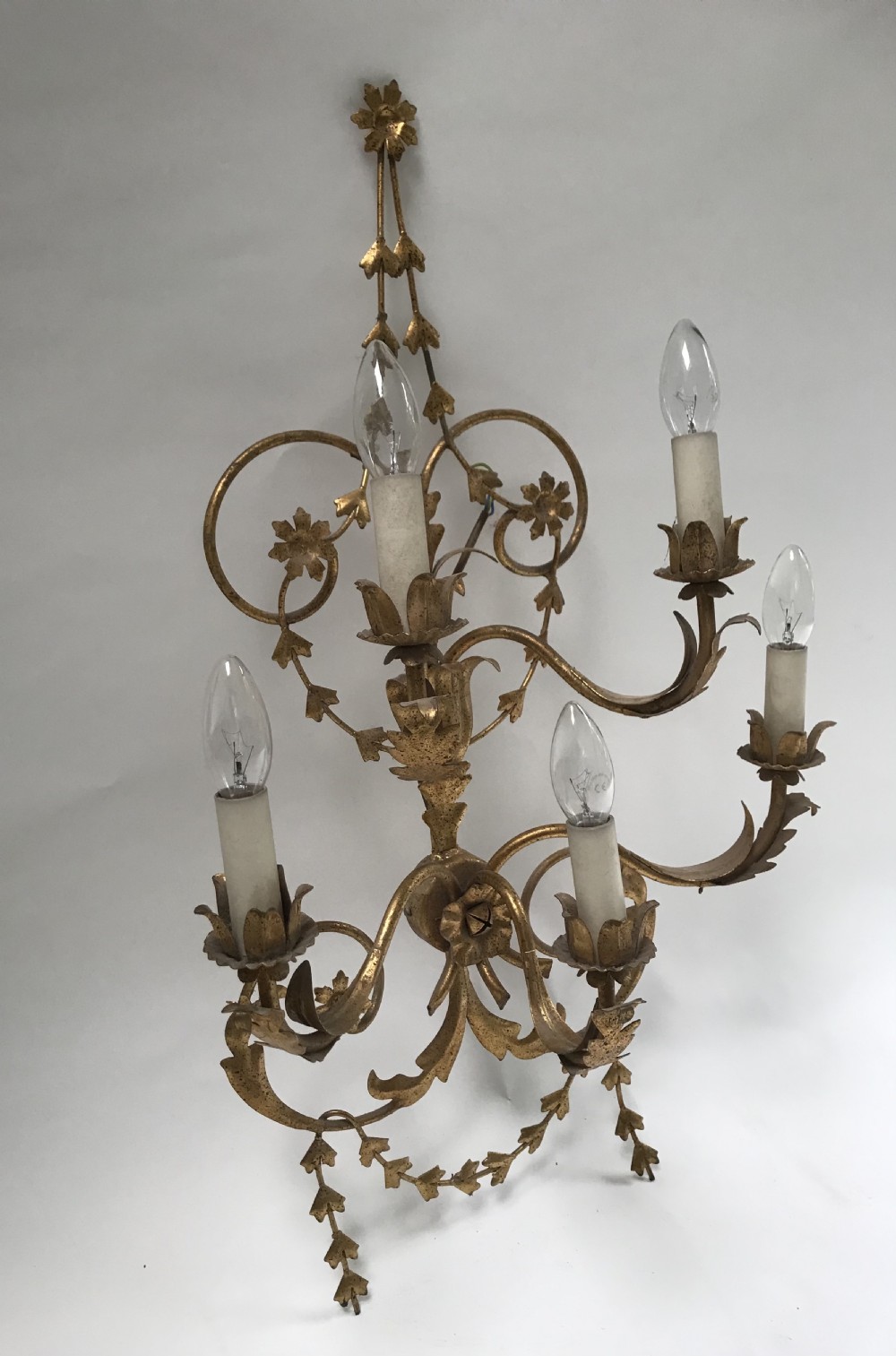 A French gilded metal five-light wall sconce decorated with scrollwork, leaf foliage, and flower-shaped candle cups. View VIII