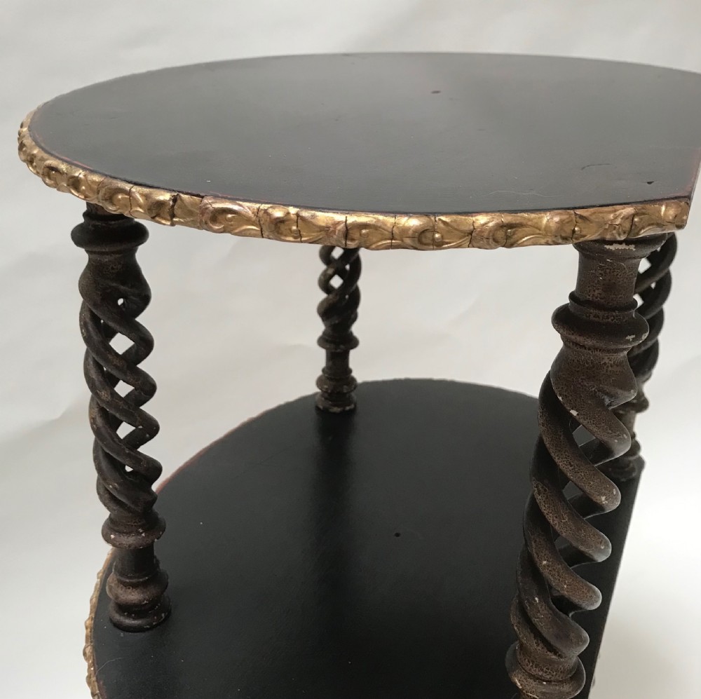 A three-tiered oval French whatnot table painted black with carved gilded borders and spiralled barley twist columns. View II