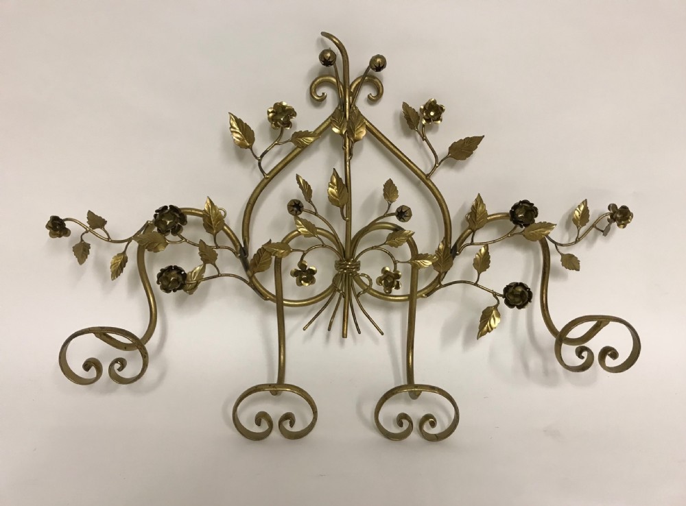 A decorative French gilded metal wall-mounted hook rack featuring elaborate scrollwork, sculpted metal leaves, and flower motifs with four bottom hooks.