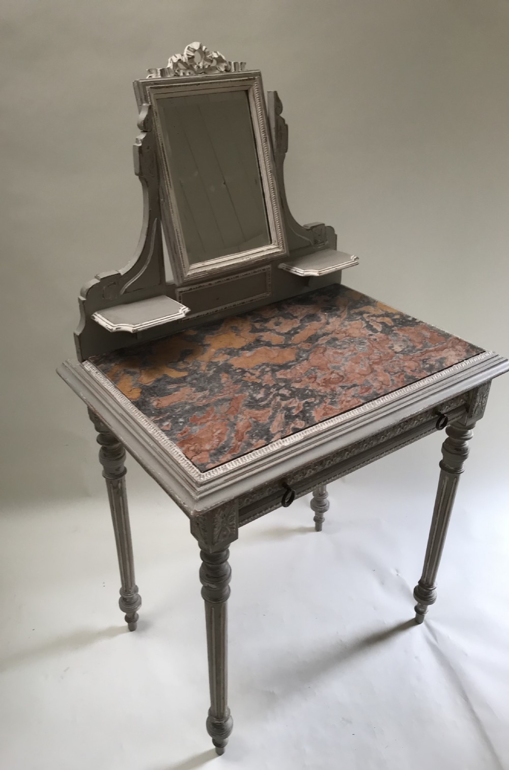 A French painted grey dressing table featuring a variegated reddish-brown marble top, an adjustable central mirror with a carved crest, two small side shelves, and tapered fluted legs. View IV
