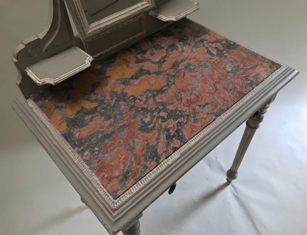 A French painted grey dressing table featuring a variegated reddish-brown marble top, an adjustable central mirror with a carved crest, two small side shelves, and tapered fluted legs. View VI