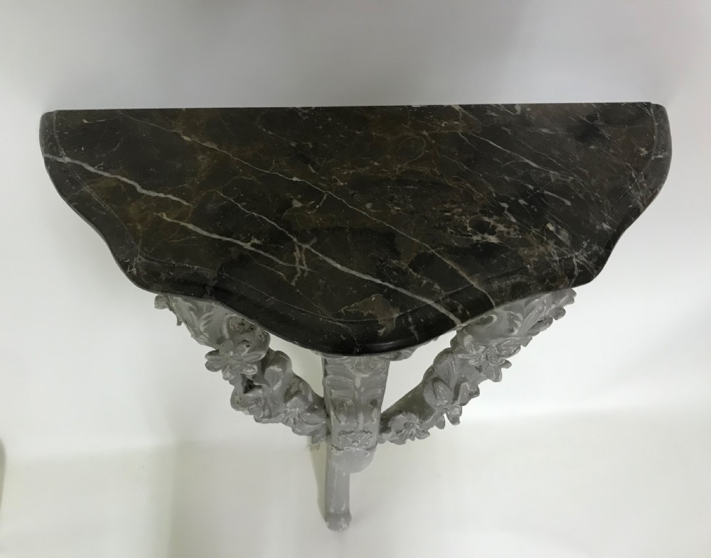 A pair of grey painted carved wood wall consoles featuring floral scroll legs and fitted black veined marble tops. View III