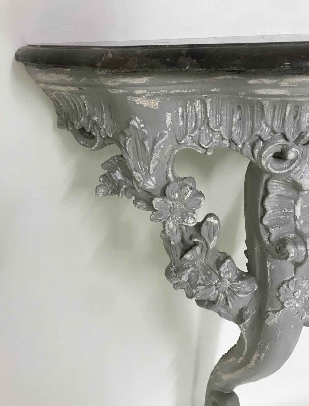 A pair of grey painted carved wood wall consoles featuring floral scroll legs and fitted black veined marble tops. View IV