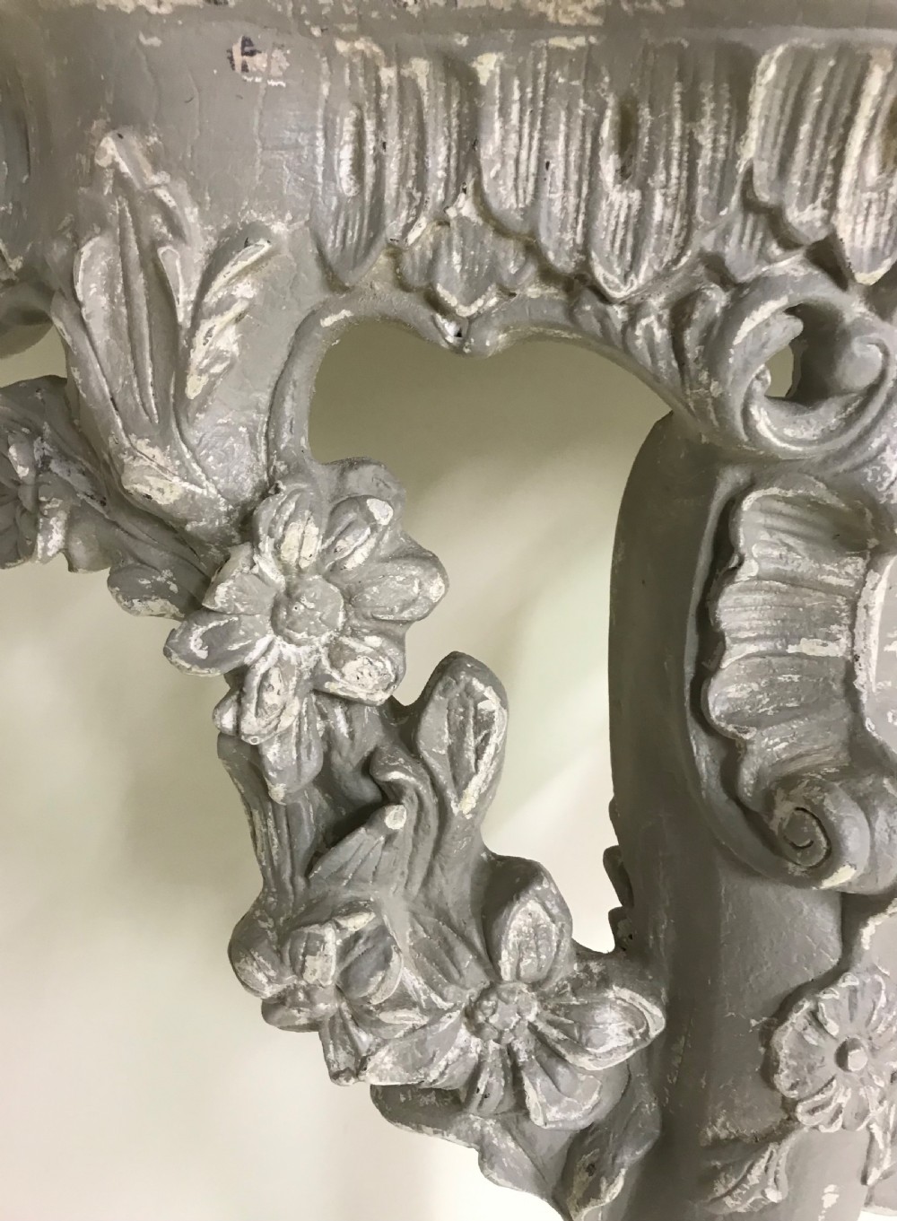 A pair of grey painted carved wood wall consoles featuring floral scroll legs and fitted black veined marble tops. View XI