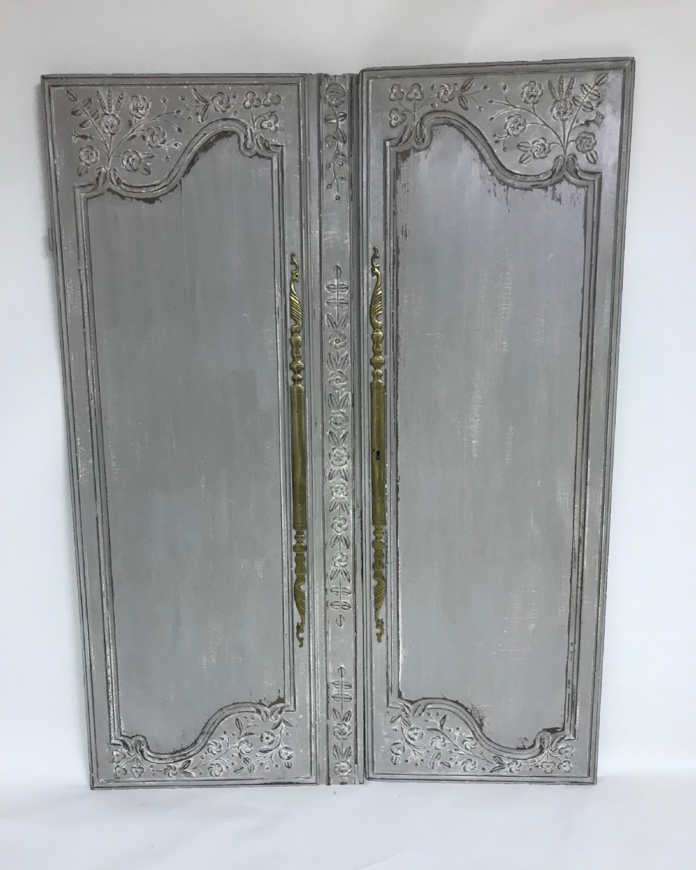 A pair of grey painted antique French doors featuring hand-carved floral panels and long brass handles. View II