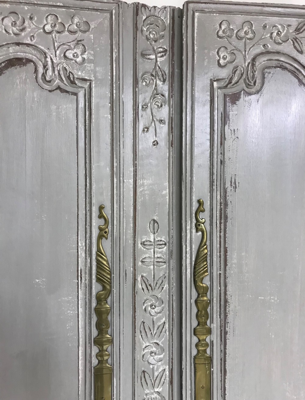 A pair of grey painted antique French doors featuring hand-carved floral panels and long brass handles. View VI