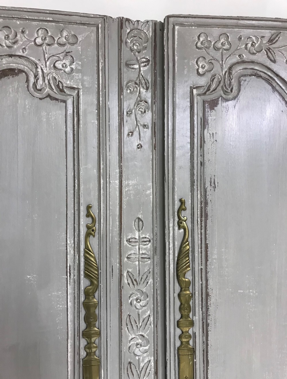 A pair of grey painted antique French doors featuring hand-carved floral panels and long brass handles. View VII