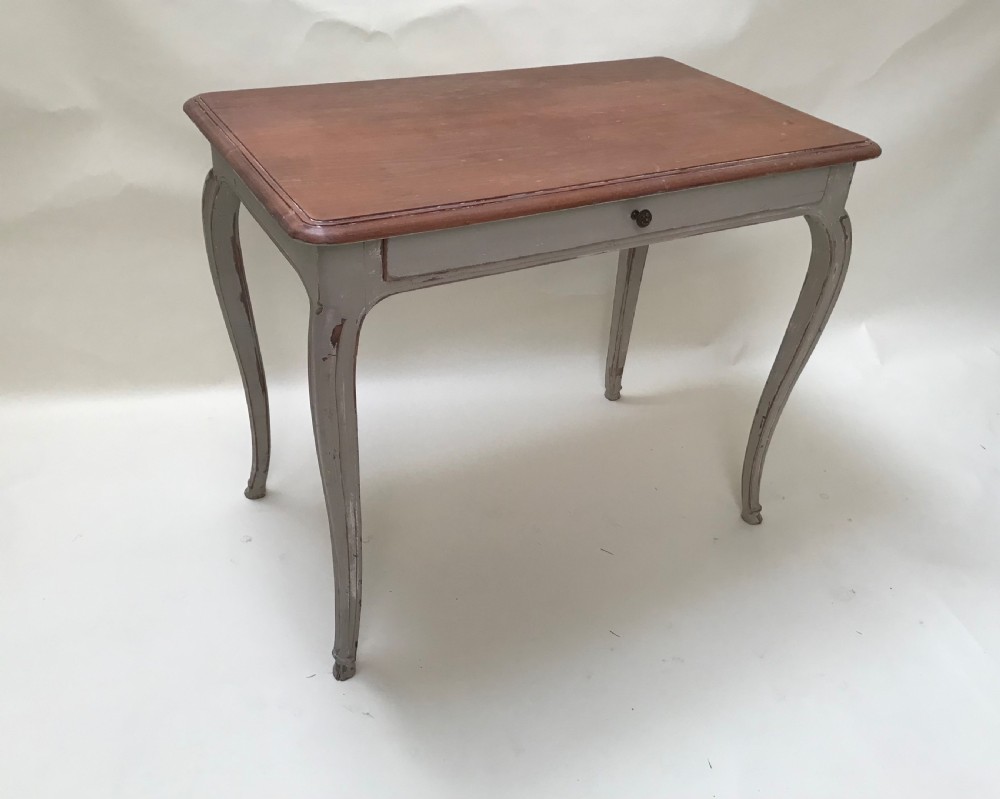A French provincial style table featuring a natural walnut wood top, a grey painted base with cabriole legs, and a single drawer.
