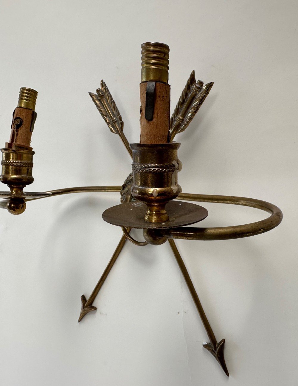 A pair of French cast brass wall sconces featuring crossed arrow backplates centred by lion masks with ring handles and two curving candle arms. View III