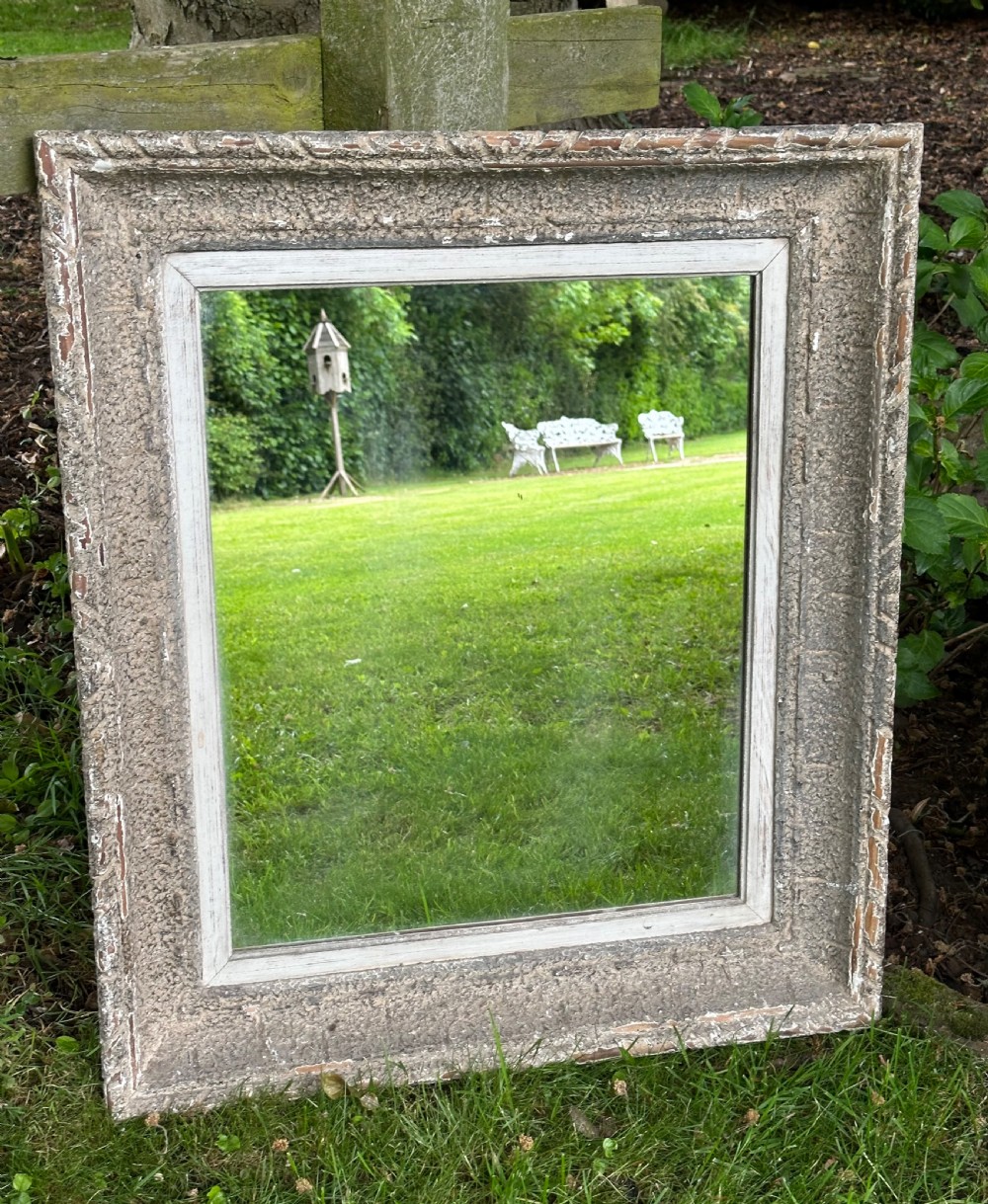 A rectangular wall mirror featuring a heavily distressed pale grey painted wooden frame with carved edge details.