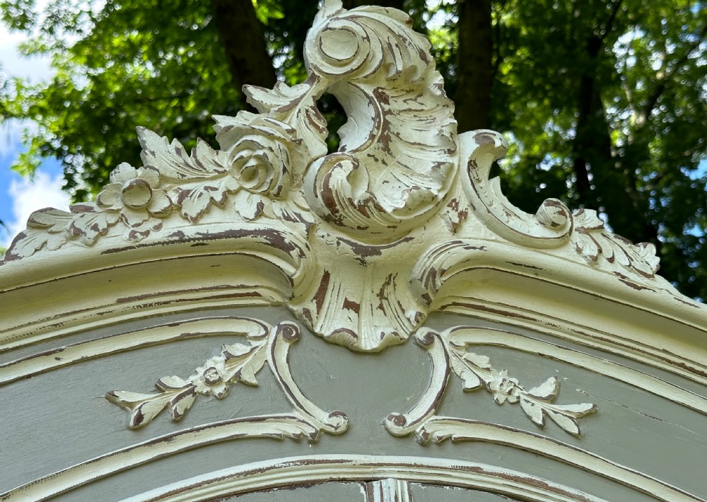 A tall grey and off-white painted French armoire featuring arched mirrored double doors, carved cresting at the top, and short cabriole legs. View III