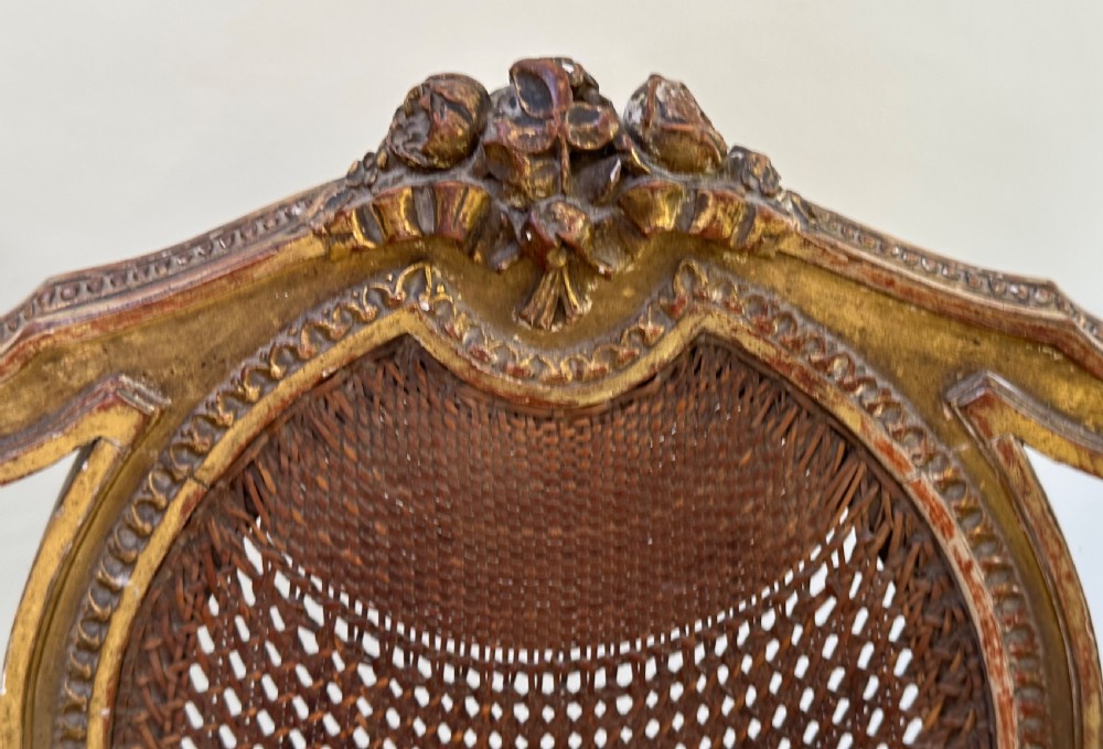 A Louis XVI style French giltwood sofa featuring a curved frame, hand-woven cane backrest and seat, and fluted legs. View II