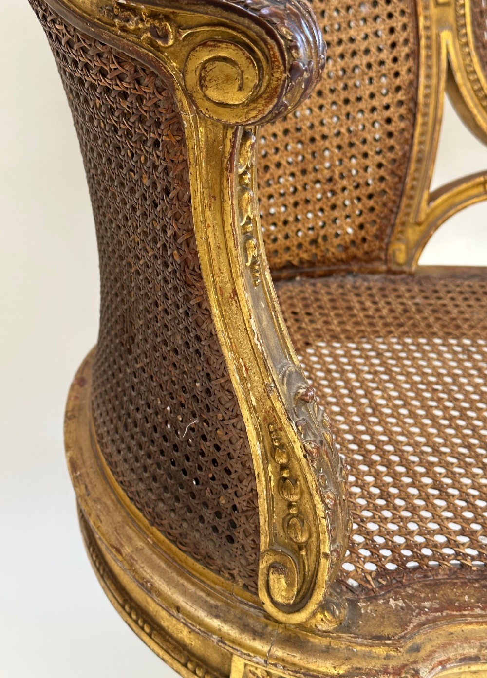 A Louis XVI style French giltwood sofa featuring a curved frame, hand-woven cane backrest and seat, and fluted legs. View VII