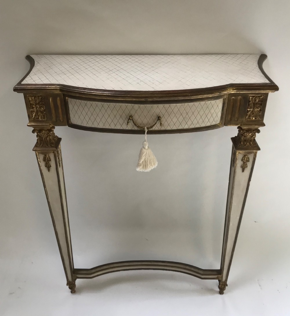 A French Neoclassical style console table with a cream diamond-patterned top, central drawer with a tassel pull, and gilded tapered legs.
