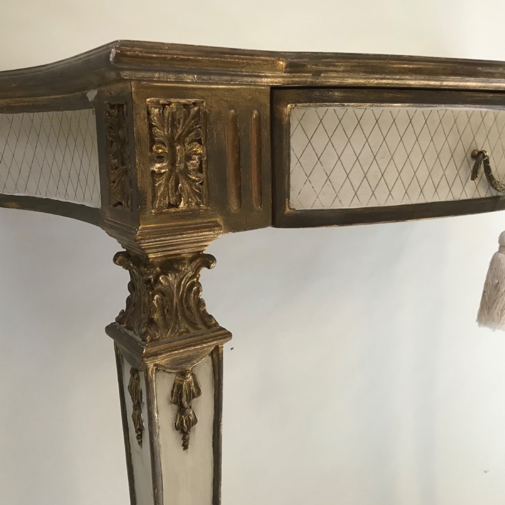 A French Neoclassical style console table with a cream diamond-patterned top, central drawer with a tassel pull, and gilded tapered legs. View VI