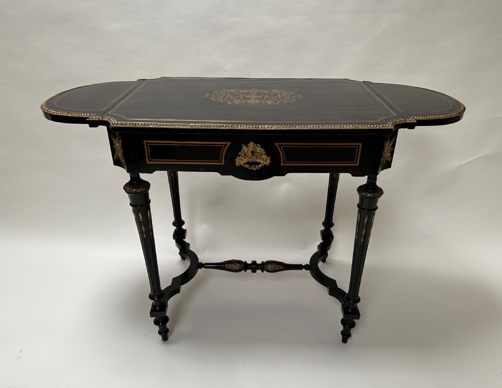 An ebonised Napoleon III drop-leaf table featuring gilt brass mounts, incised inlay, and turned legs joined by a curved stretcher. View II