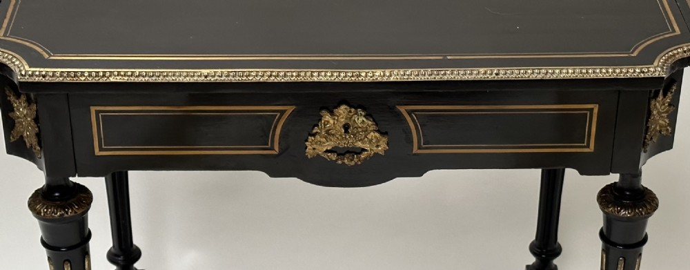 An ebonised Napoleon III drop-leaf table featuring gilt brass mounts, incised inlay, and turned legs joined by a curved stretcher. View IV