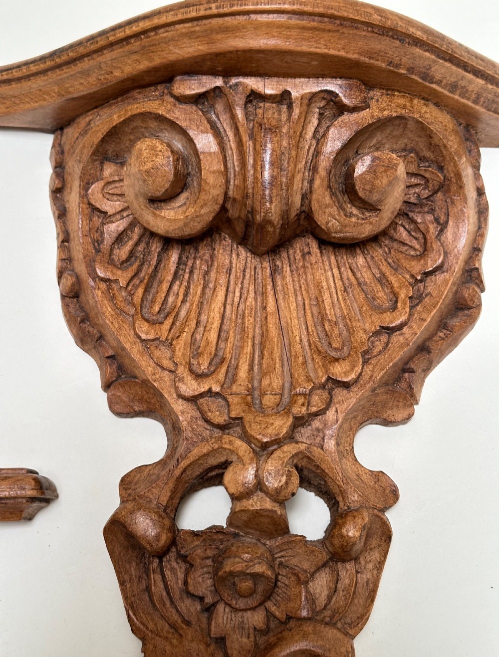 A matching pair of hand-carved warm brown wooden wall brackets featuring ornate scrollwork, shell fluting, and floral motifs. View IV