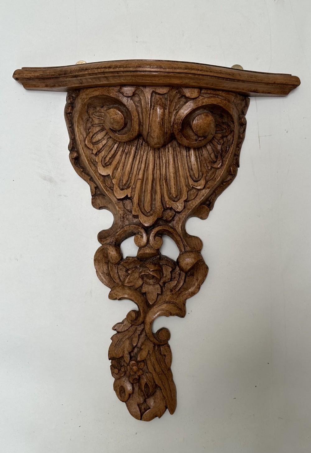 A matching pair of hand-carved warm brown wooden wall brackets featuring ornate scrollwork, shell fluting, and floral motifs. View V