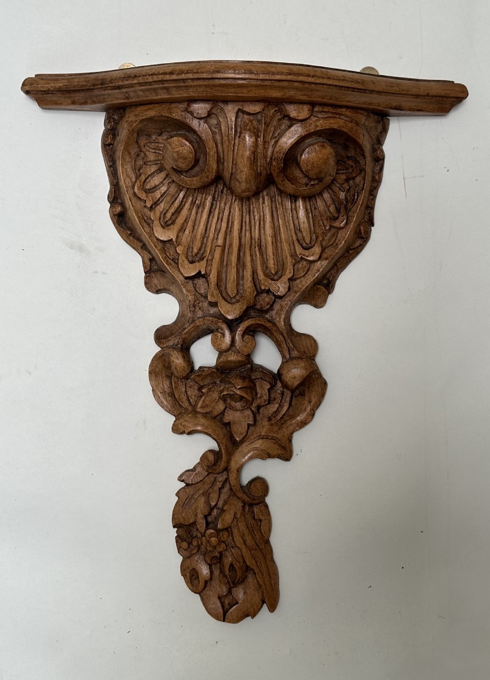 A matching pair of hand-carved warm brown wooden wall brackets featuring ornate scrollwork, shell fluting, and floral motifs. View VI