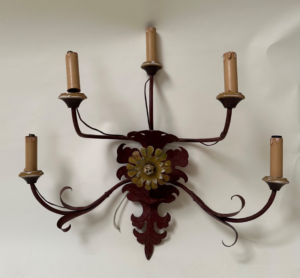 A pair of large French wrought iron five-light wall sconces finished in dark red paint with central gilt floral rosettes and sweeping scrolling arms. View II