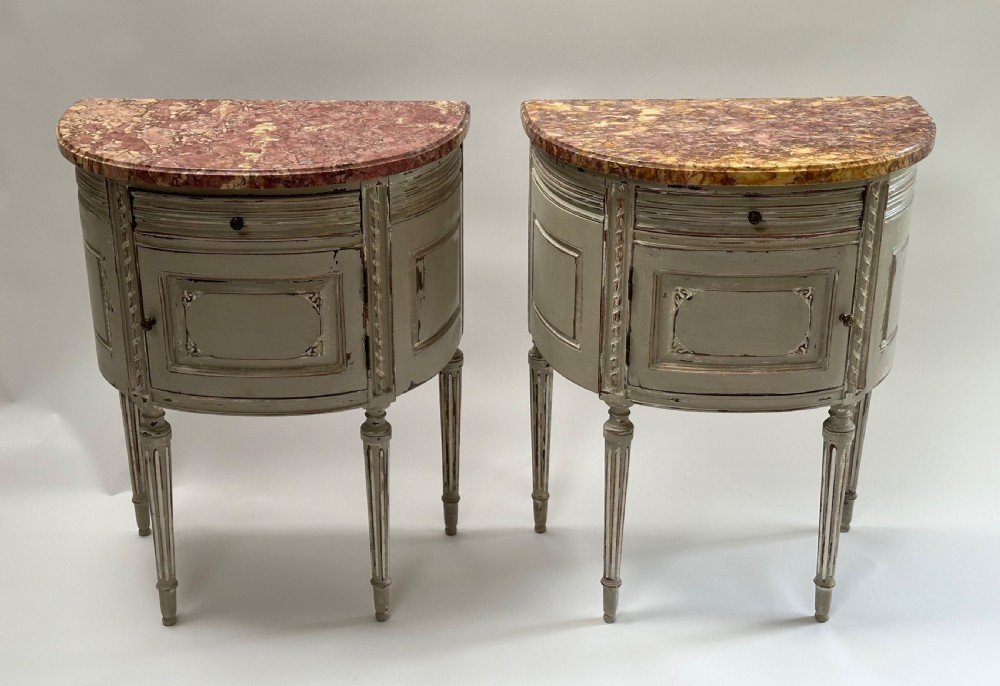 A pair of grey painted demi-lune bedside tables with variegated red marble tops and fluted tapering legs.