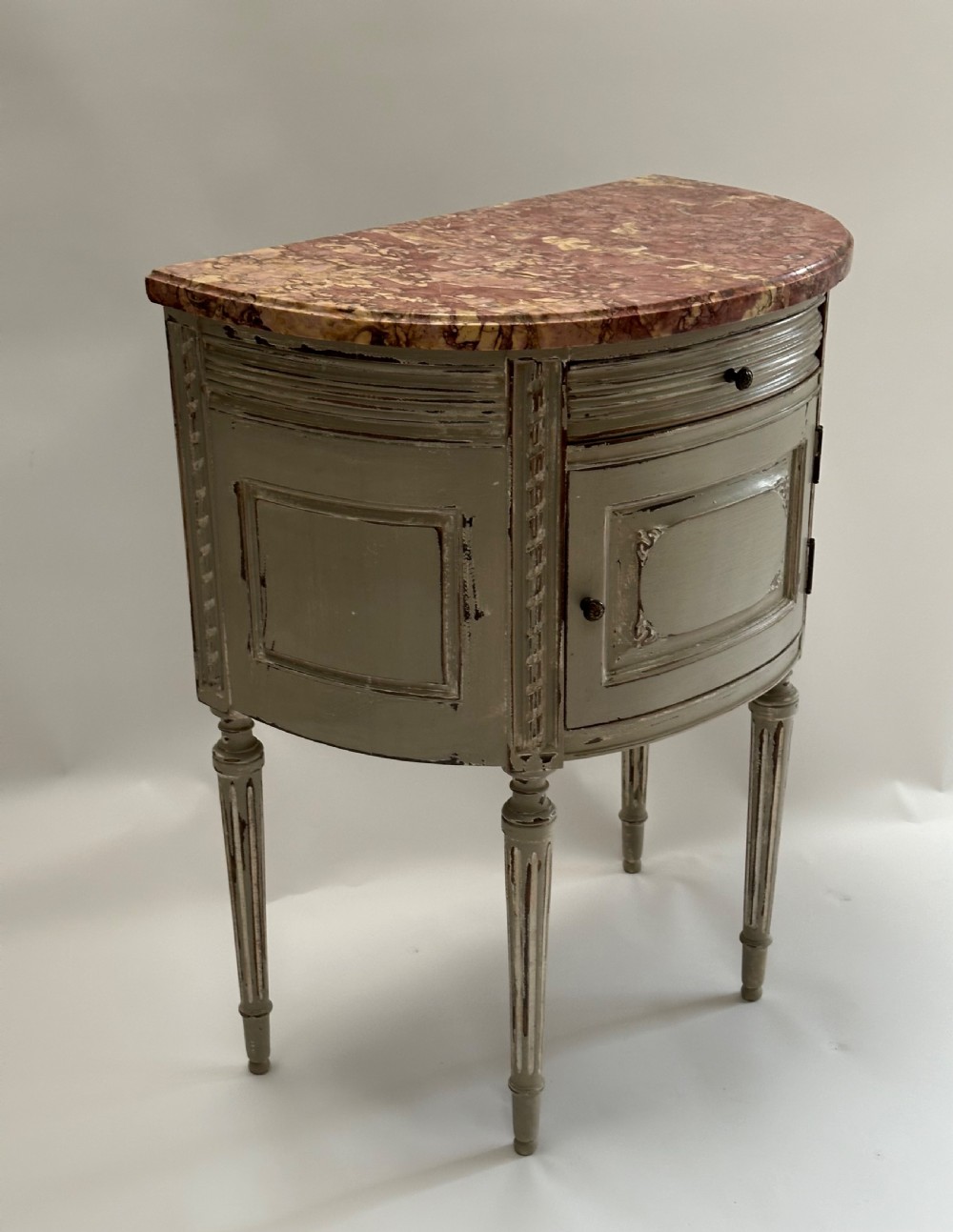 A pair of grey painted demi-lune bedside tables with variegated red marble tops and fluted tapering legs. View IV