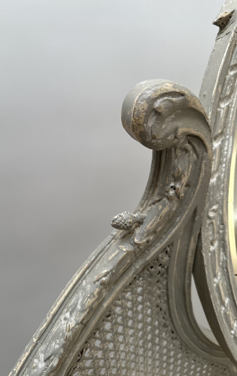 A grey painted French style dressing table with a cane back panel, oval top mirror, small side drawers, and slender carved legs. View IV
