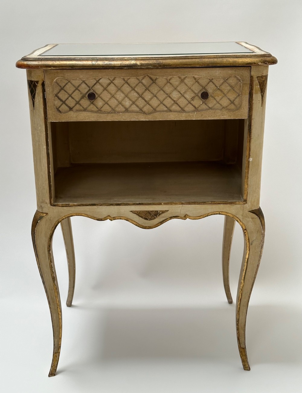 A pair of cream and gold Florentine bedside tables featuring mirrored tops, open lower compartments, carved lattice drawers, and slender cabriole legs. View V
