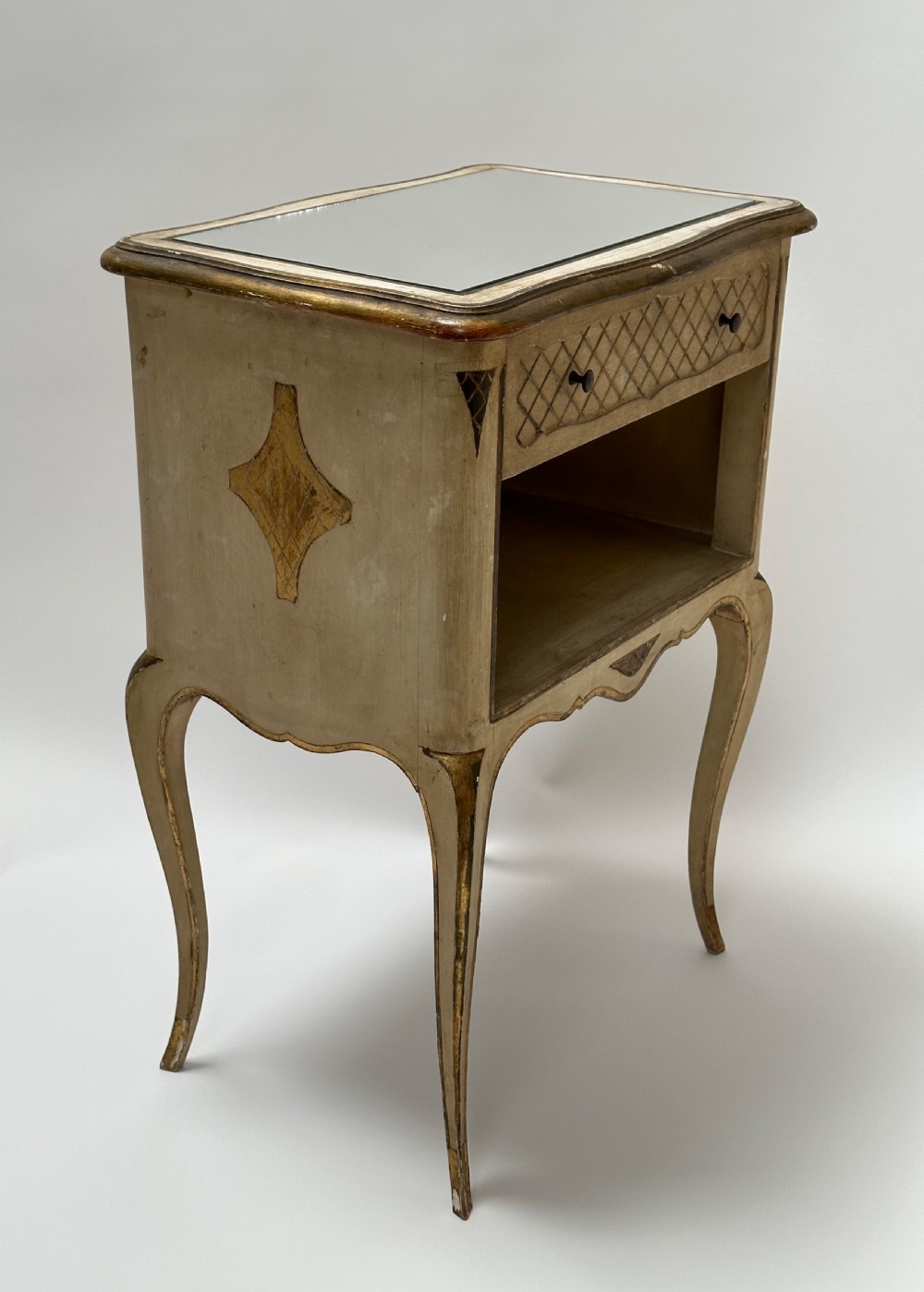 A pair of cream and gold Florentine bedside tables featuring mirrored tops, open lower compartments, carved lattice drawers, and slender cabriole legs. View VI