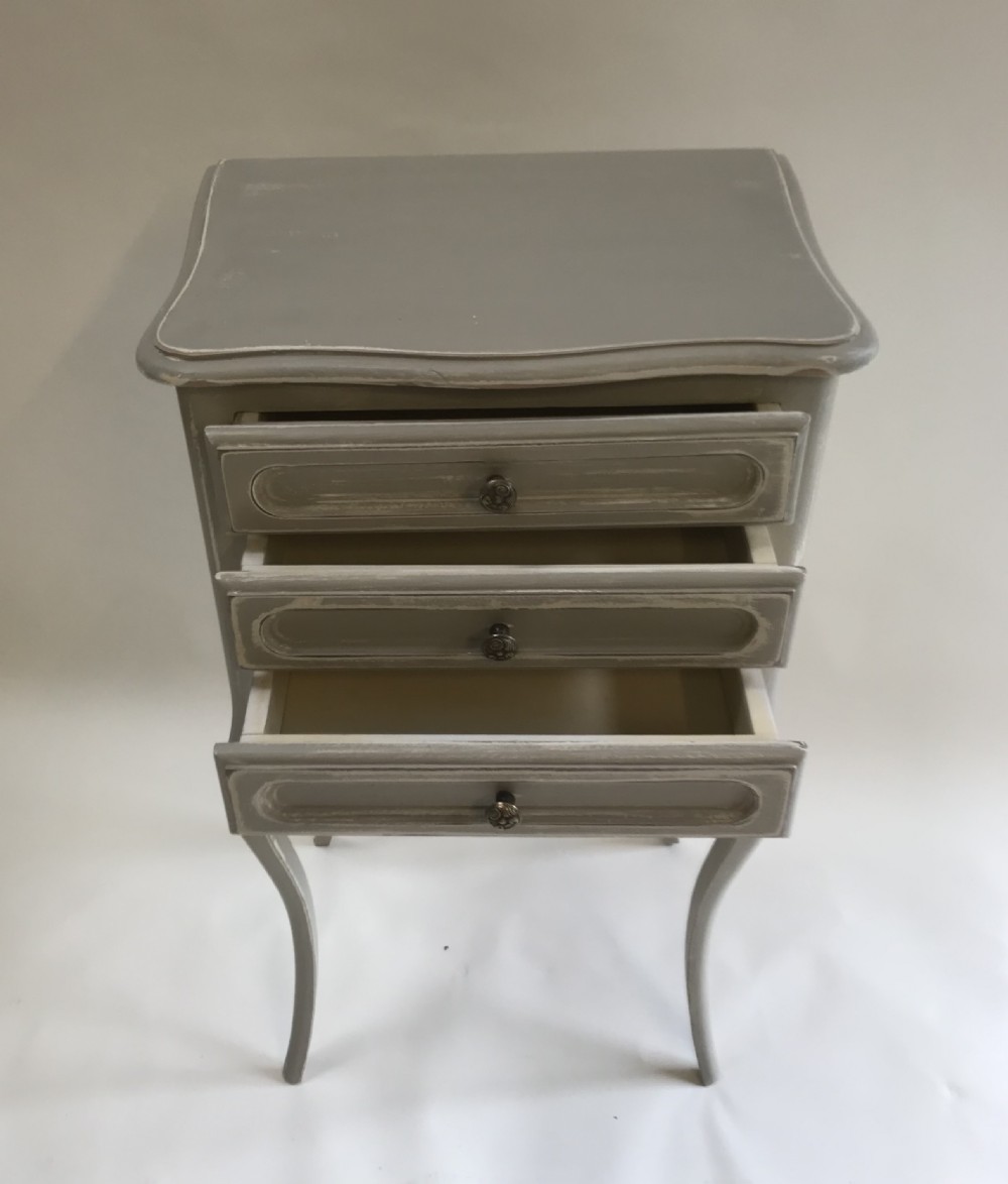 A pair of slender grey painted French provincial bedside tables featuring three drawers and tall cabriole legs. View III
