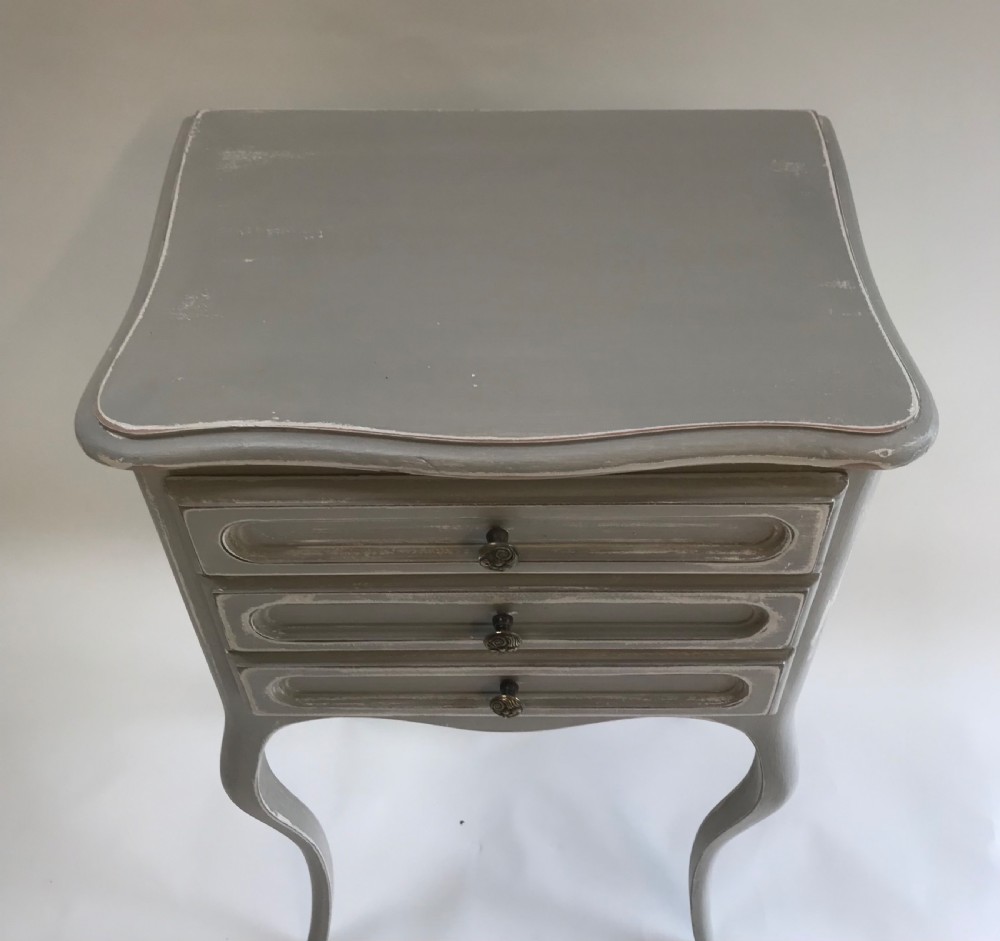 A pair of slender grey painted French provincial bedside tables featuring three drawers and tall cabriole legs. View IV