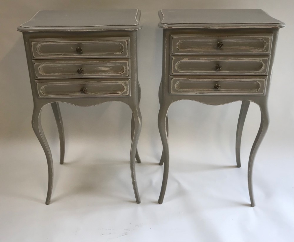 A pair of slender grey painted French provincial bedside tables featuring three drawers and tall cabriole legs. View V