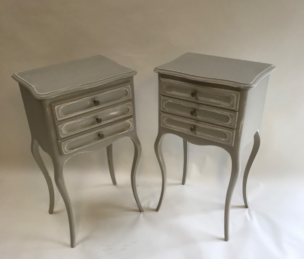 A pair of slender grey painted French provincial bedside tables featuring three drawers and tall cabriole legs. View VI