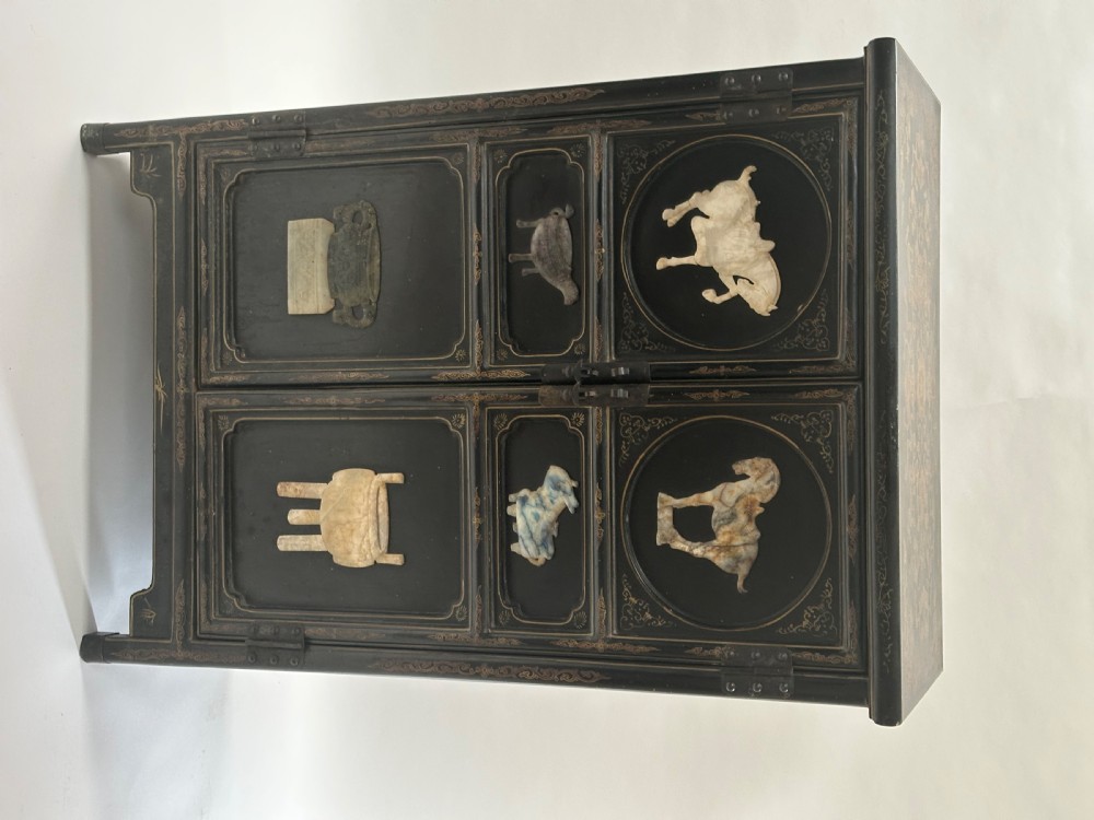 A pair of black lacquered two-door Chinoiserie cabinets featuring carved hardstone inlays of horses, animals, and vessels, topped with gilt scrollwork motifs. View II