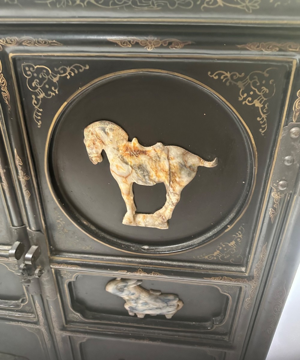 A pair of black lacquered two-door Chinoiserie cabinets featuring carved hardstone inlays of horses, animals, and vessels, topped with gilt scrollwork motifs. View III
