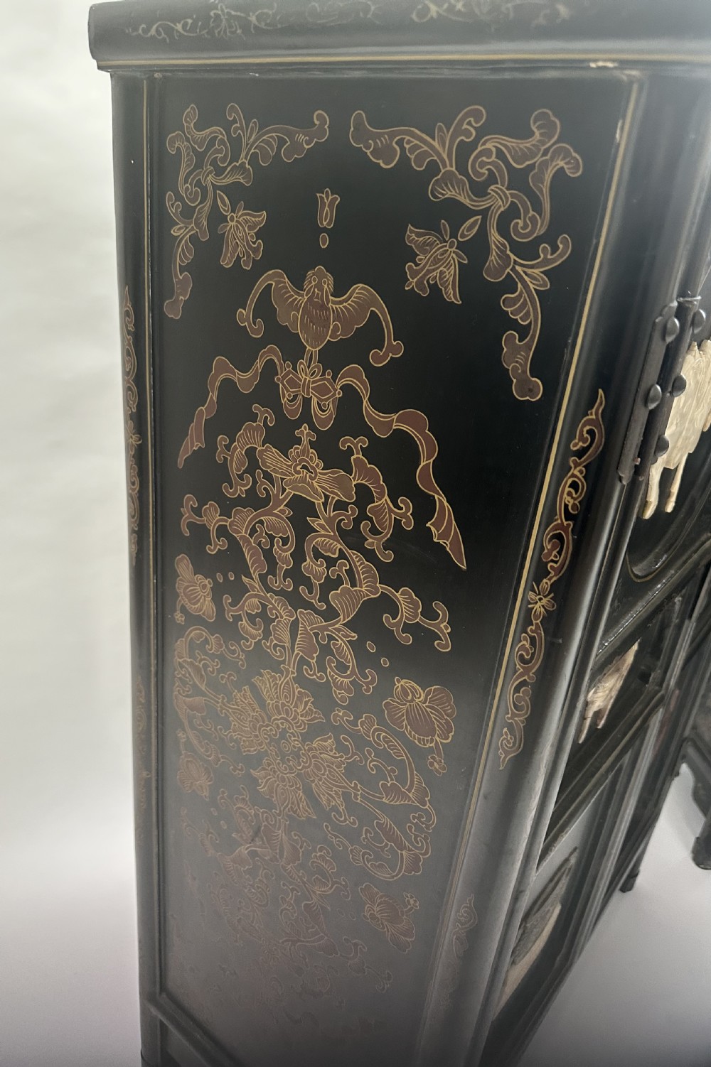 A pair of black lacquered two-door Chinoiserie cabinets featuring carved hardstone inlays of horses, animals, and vessels, topped with gilt scrollwork motifs. View VI