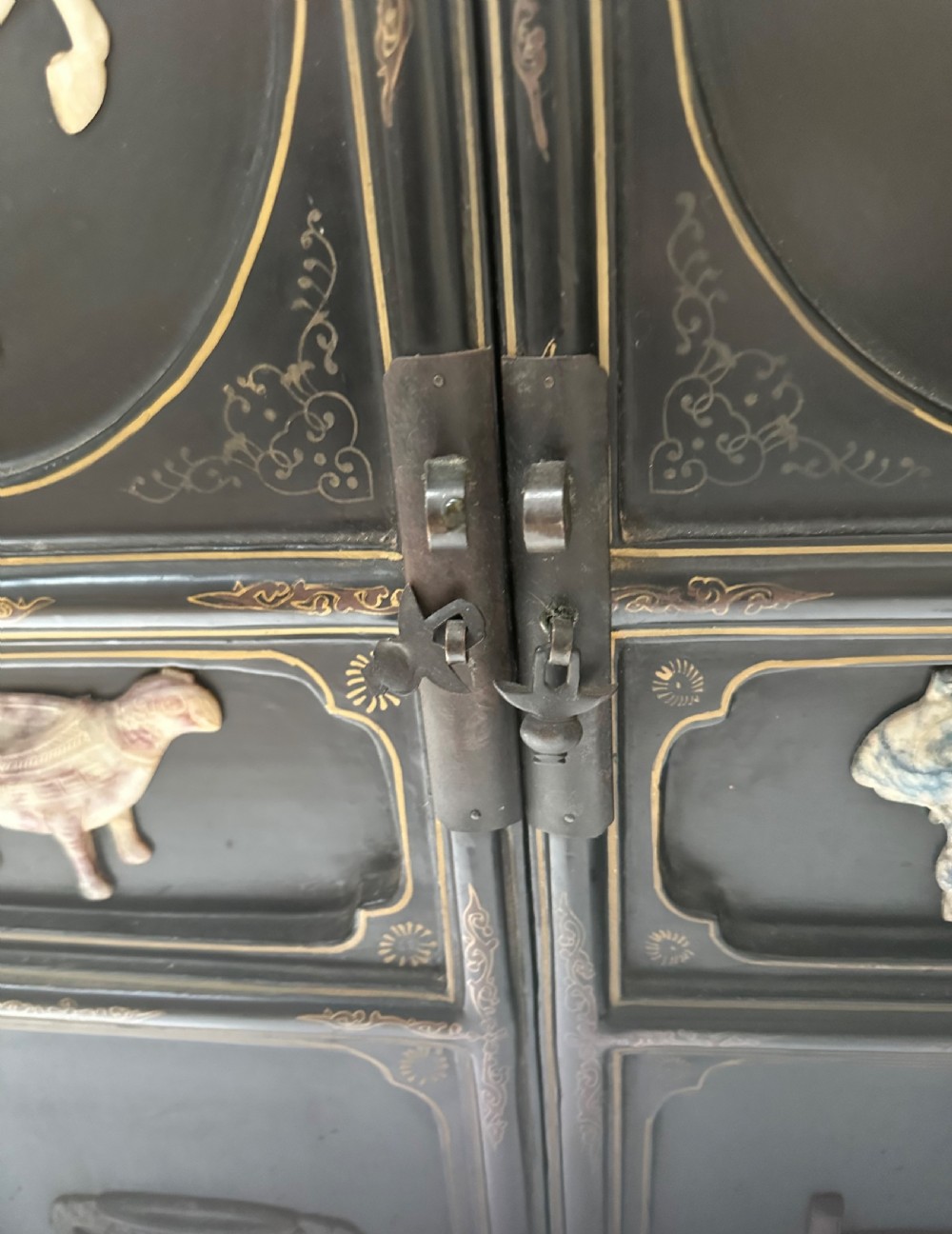 A pair of black lacquered two-door Chinoiserie cabinets featuring carved hardstone inlays of horses, animals, and vessels, topped with gilt scrollwork motifs. View VII